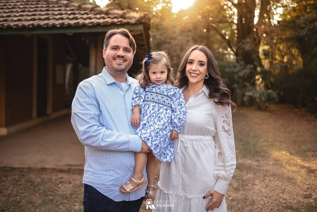 Família posando ao entardecer em frente a uma casa rústica