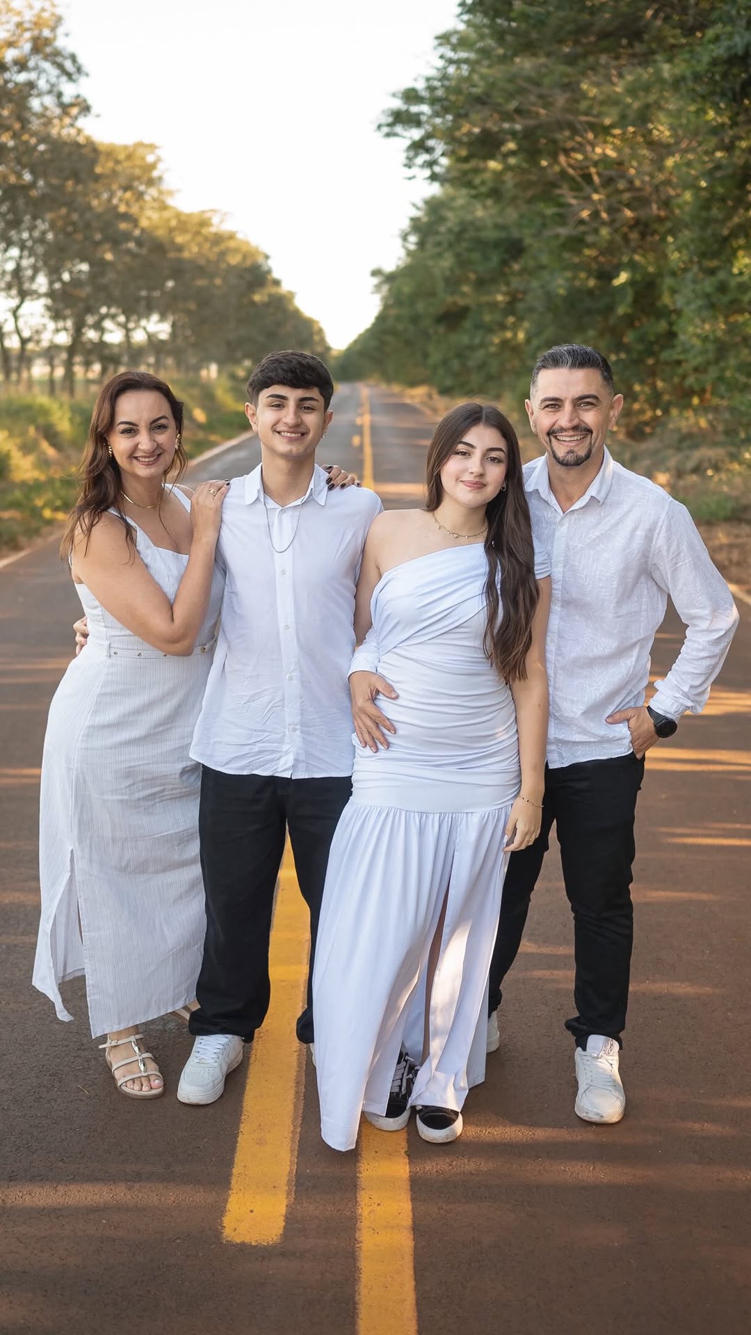 Família de quatro pessoas caminhando por uma estrada arborizada